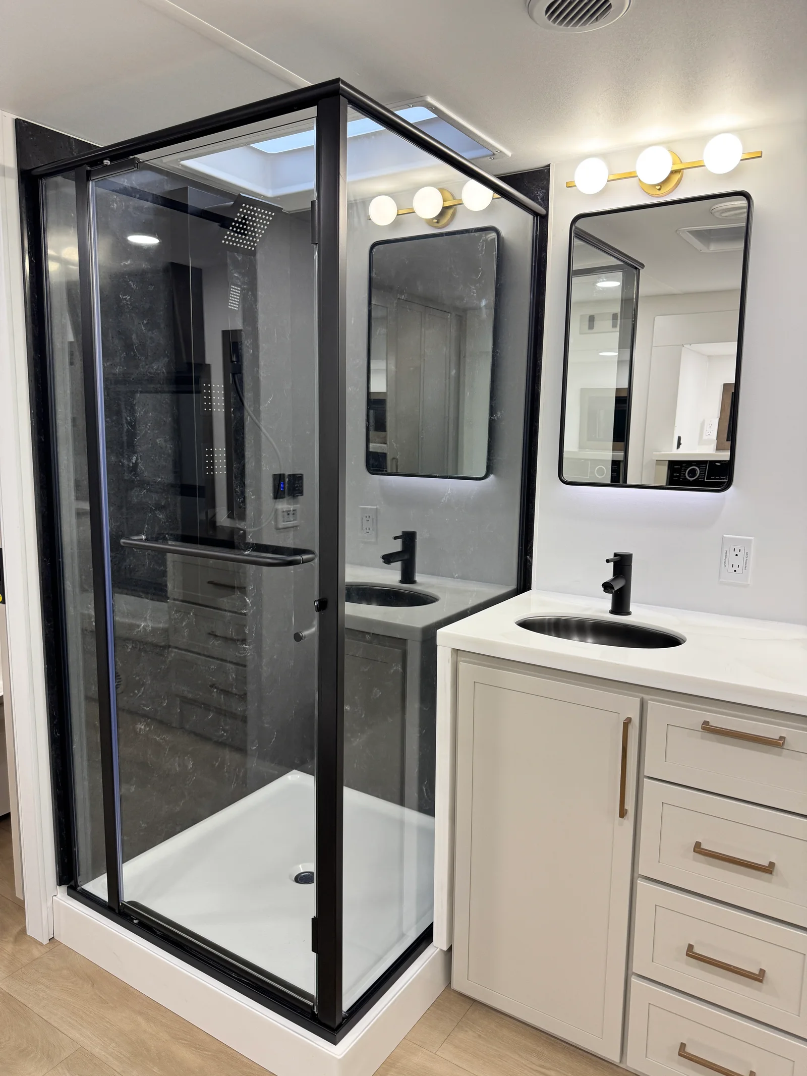Glass-enclosed shower beside the dual-sink vanity in the Aurum's front bathroom.