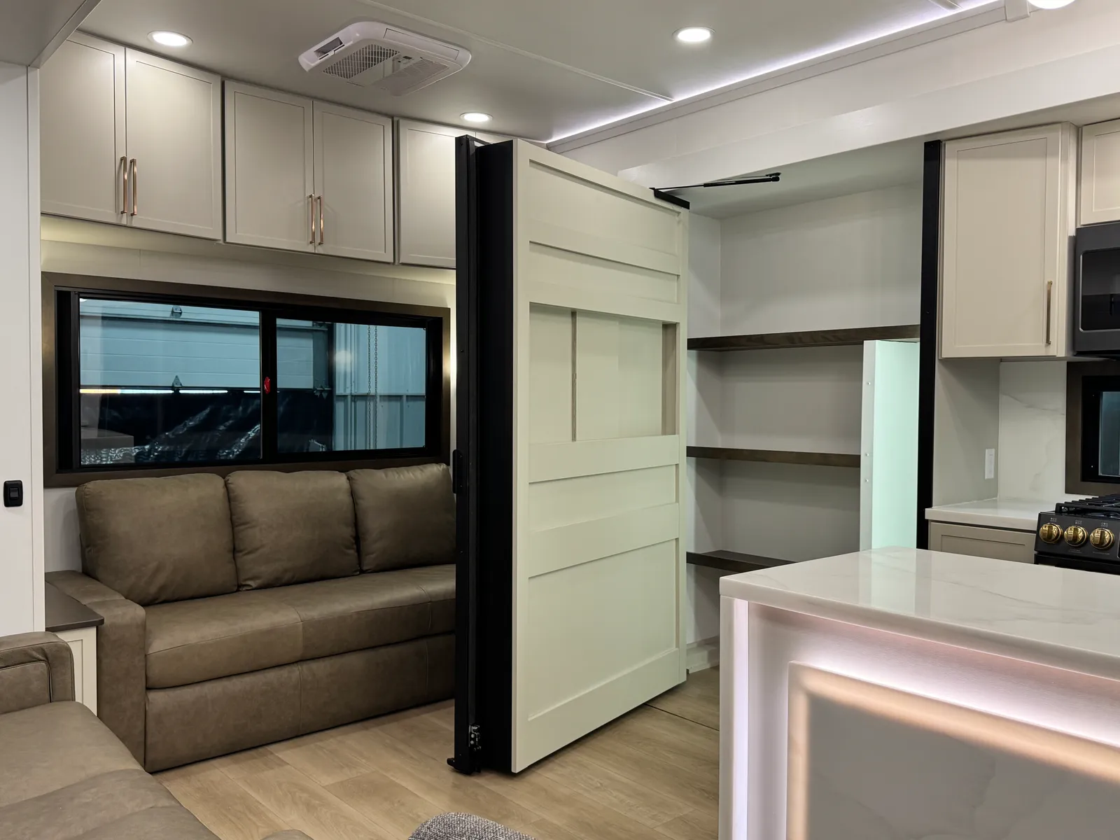 The entertainment wall swung open to reveal pantry shelving beside the sofa.