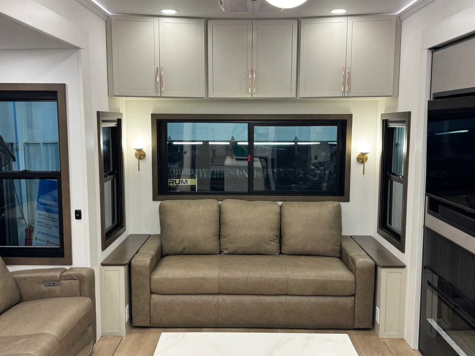 Leather sofa under the rear window with brass wall sconces on either side.
