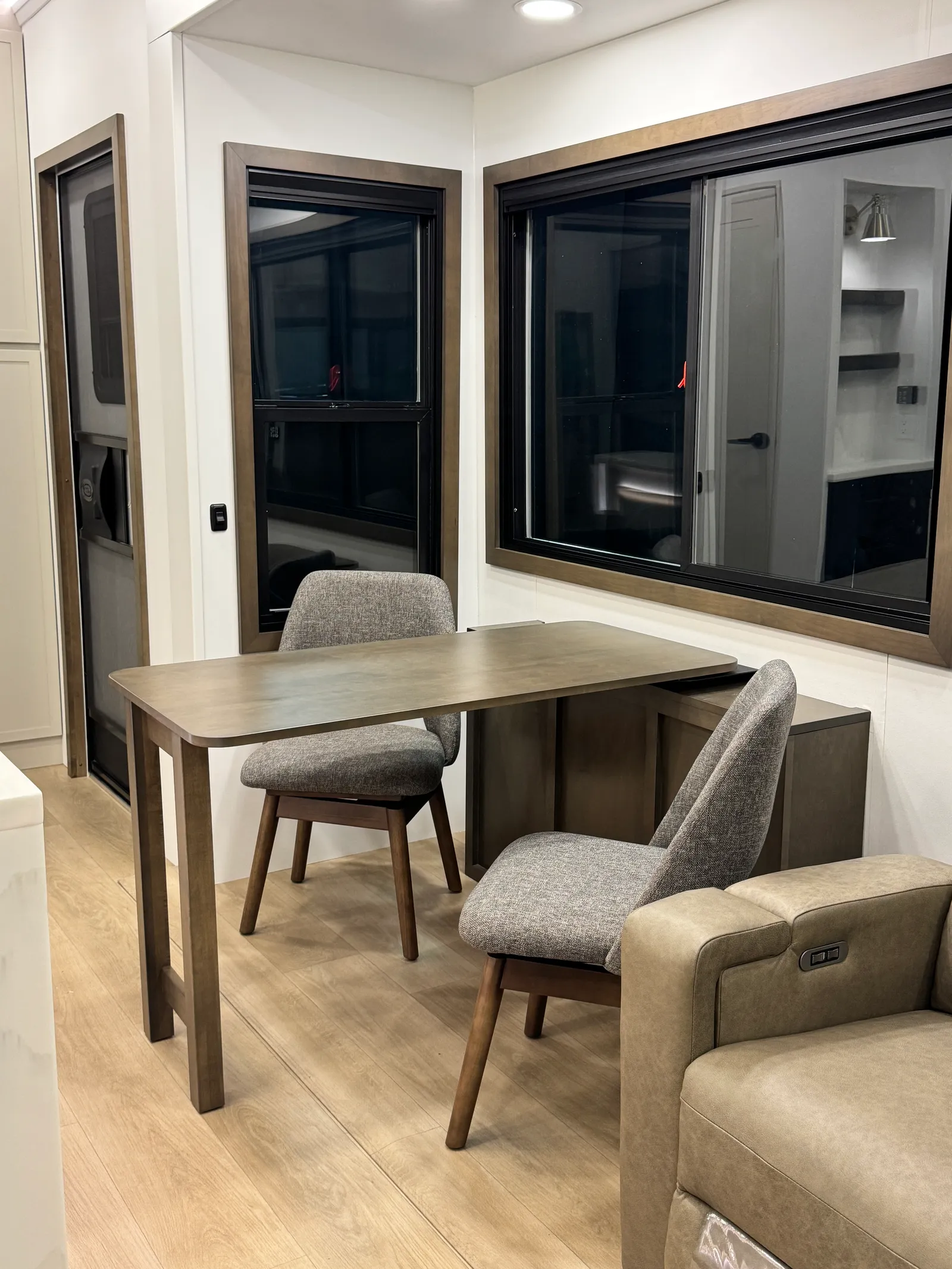 Convertible dining table with two upholstered chairs beside the windows and theater seating.