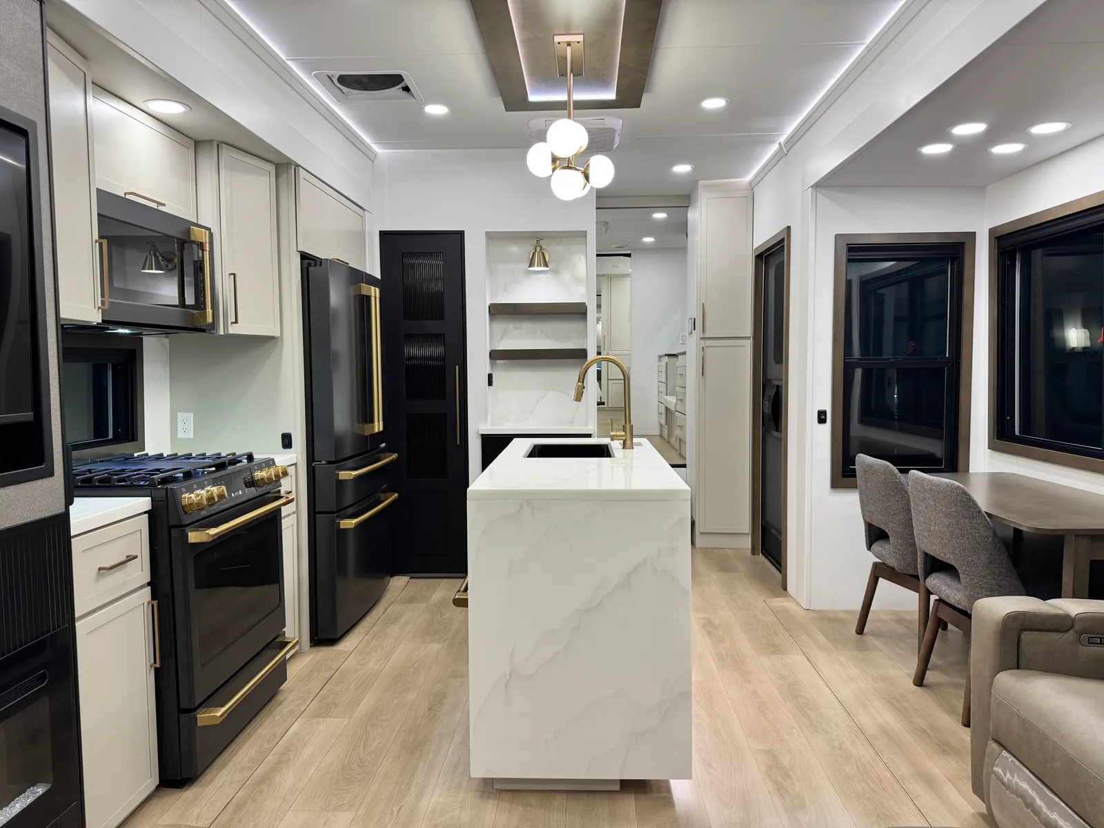 View down the kitchen past the island, range and refrigerator toward the front of the coach.