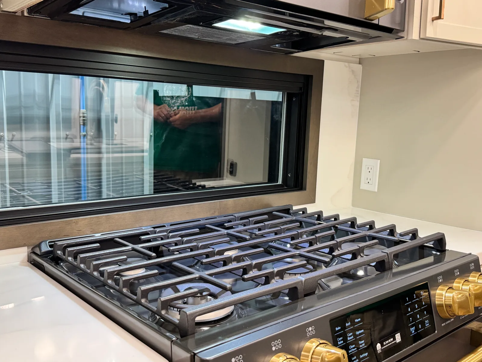 The gas cooktop's grates and gold knobs, with the window behind.