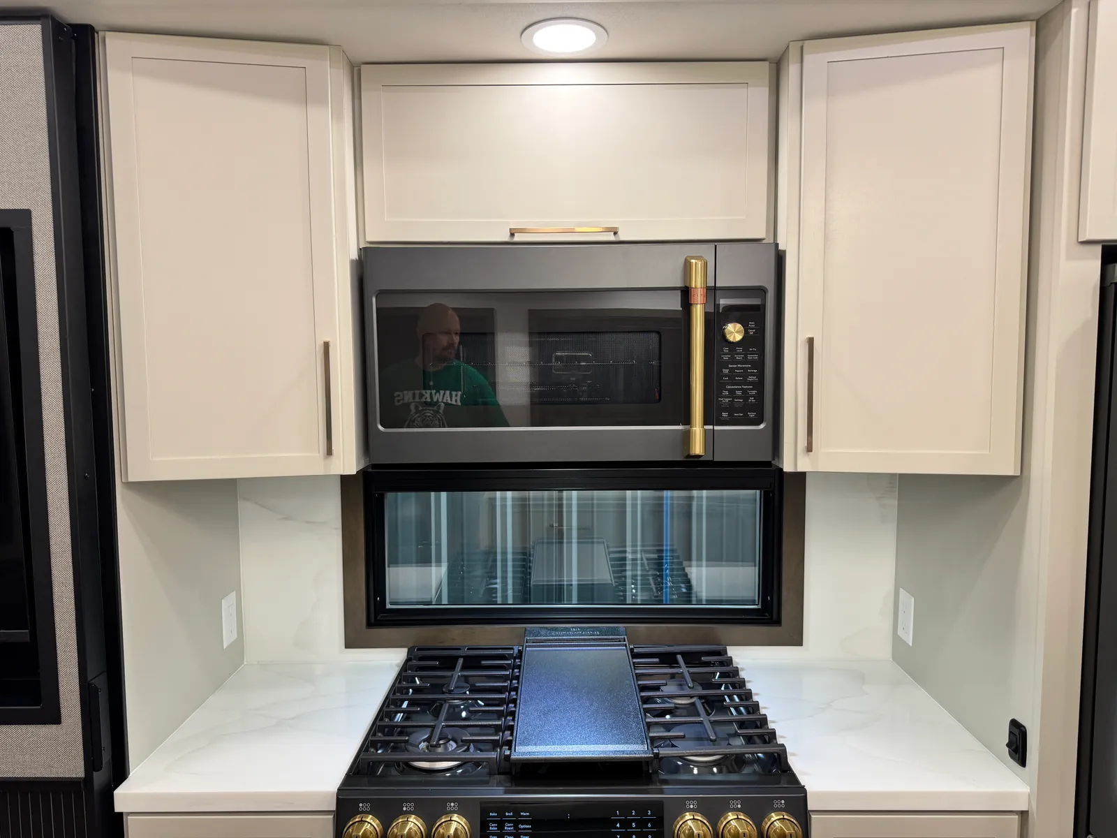 Microwave mounted above the range between upper cabinets, with the cooktop below.