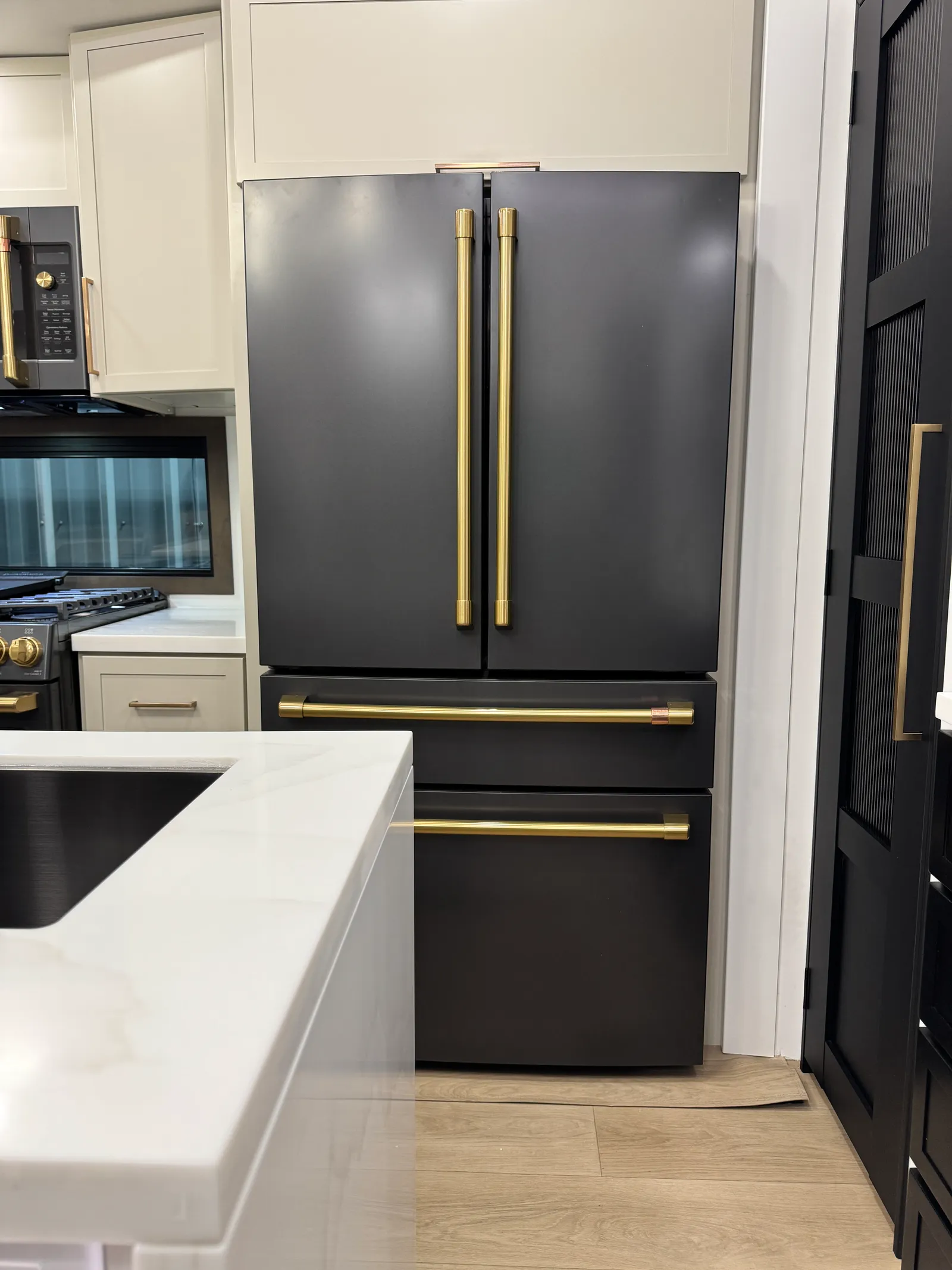 French-door refrigerator with gold handles beside the kitchen island.