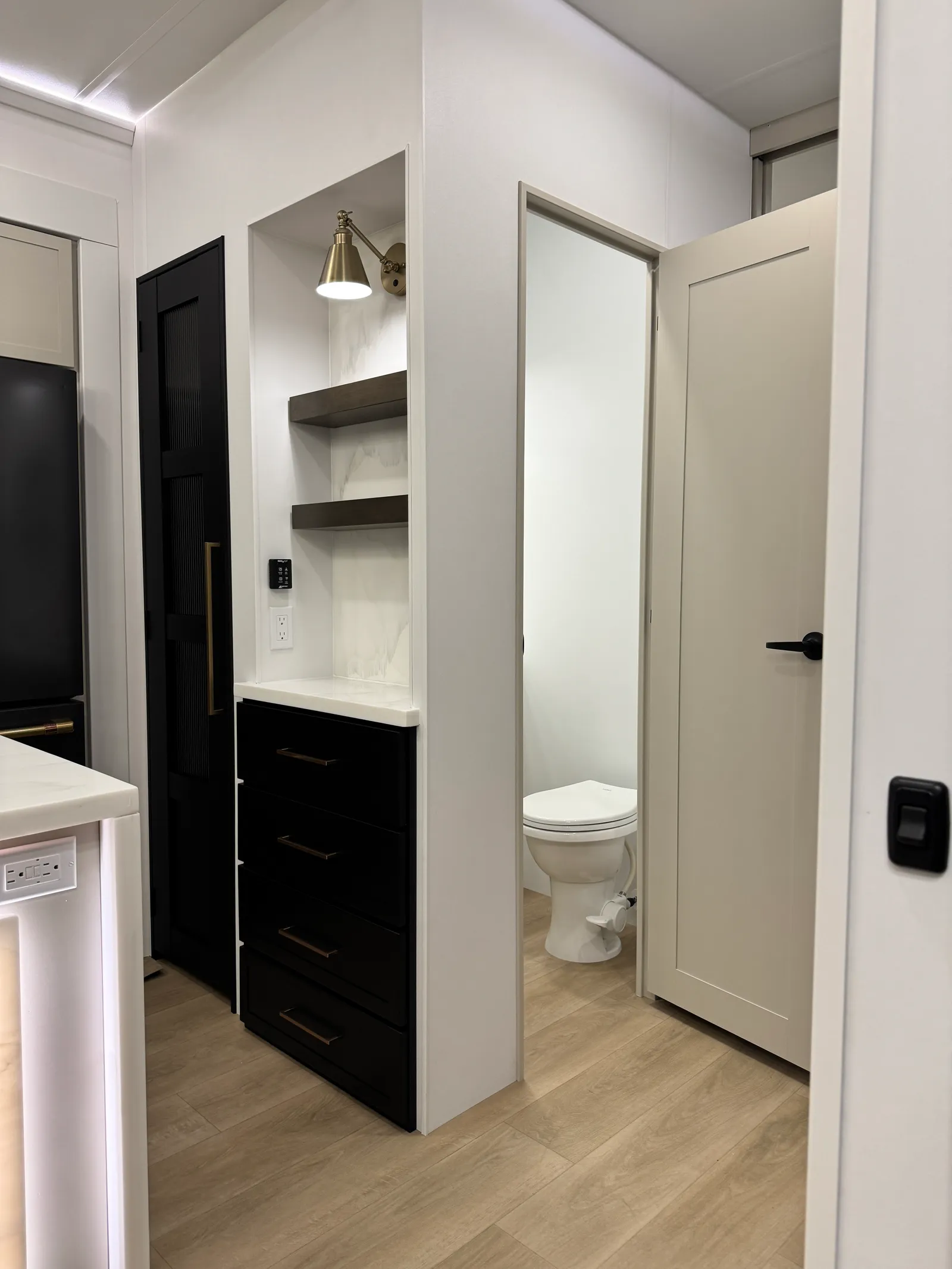 Doorway into the half bath, with a toilet visible, beside a black cabinet.