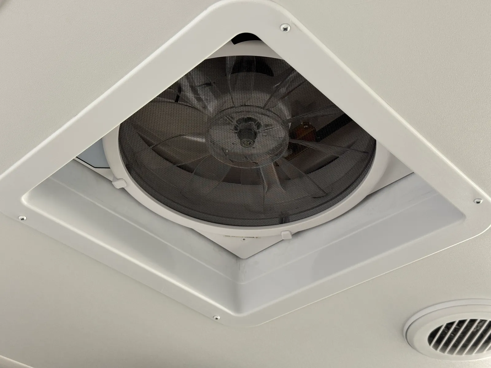 A roof vent fan in the white ceiling, seen from below.
