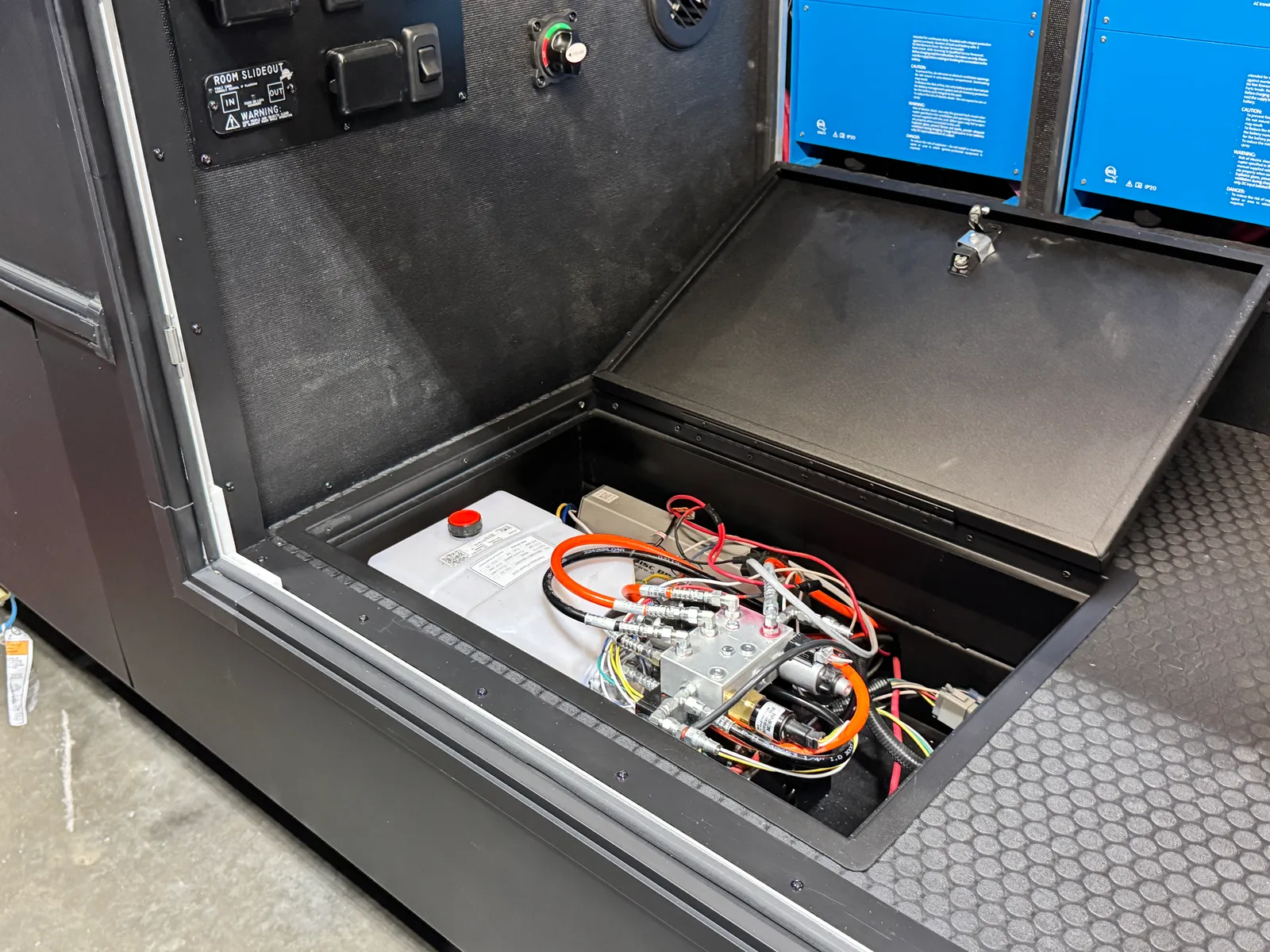 A floor hatch in the storage bay opened to show a battery and wiring.