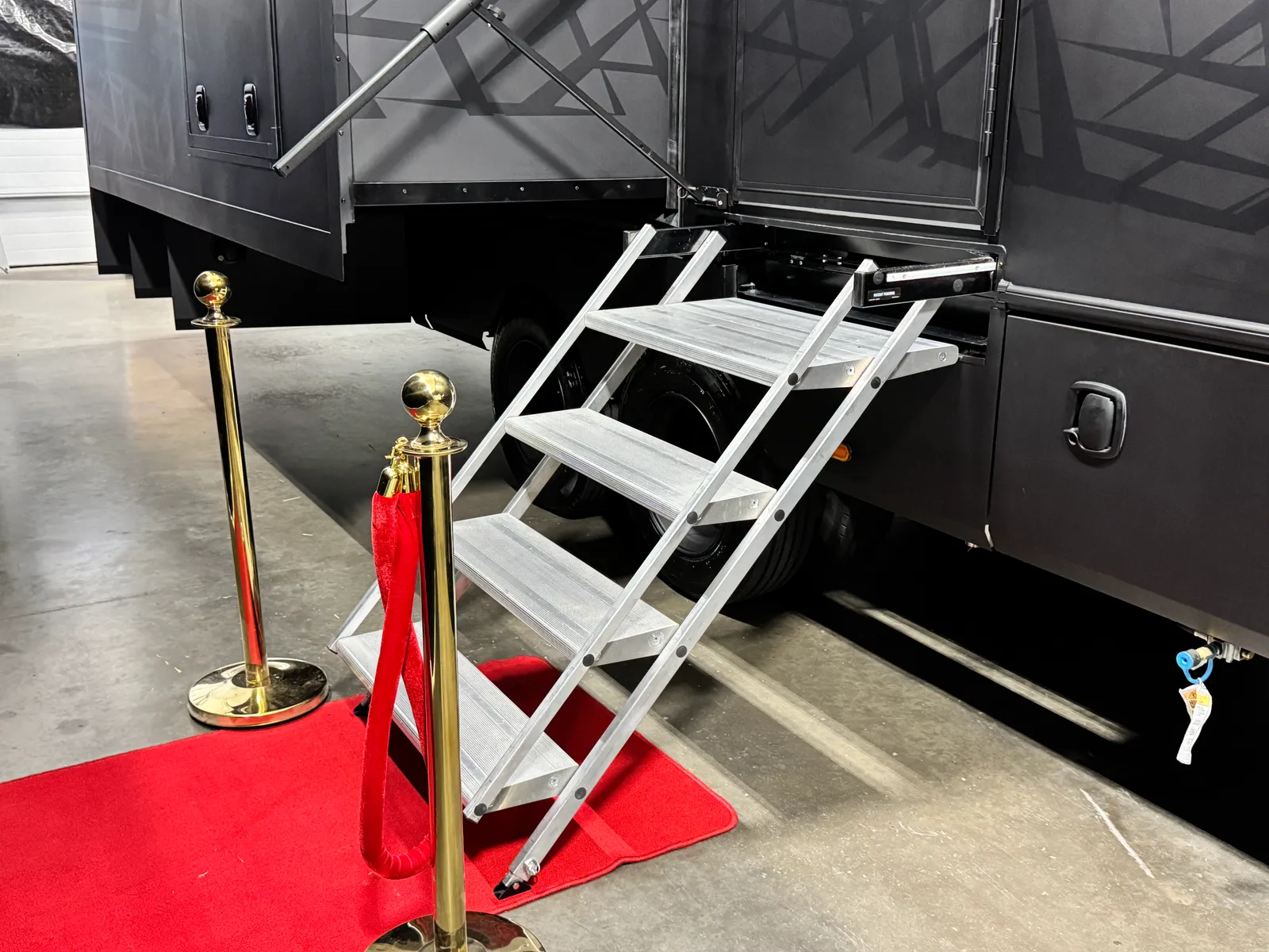 Folding aluminum entry steps lowered to a red carpet beside the Aurum's tandem wheels.