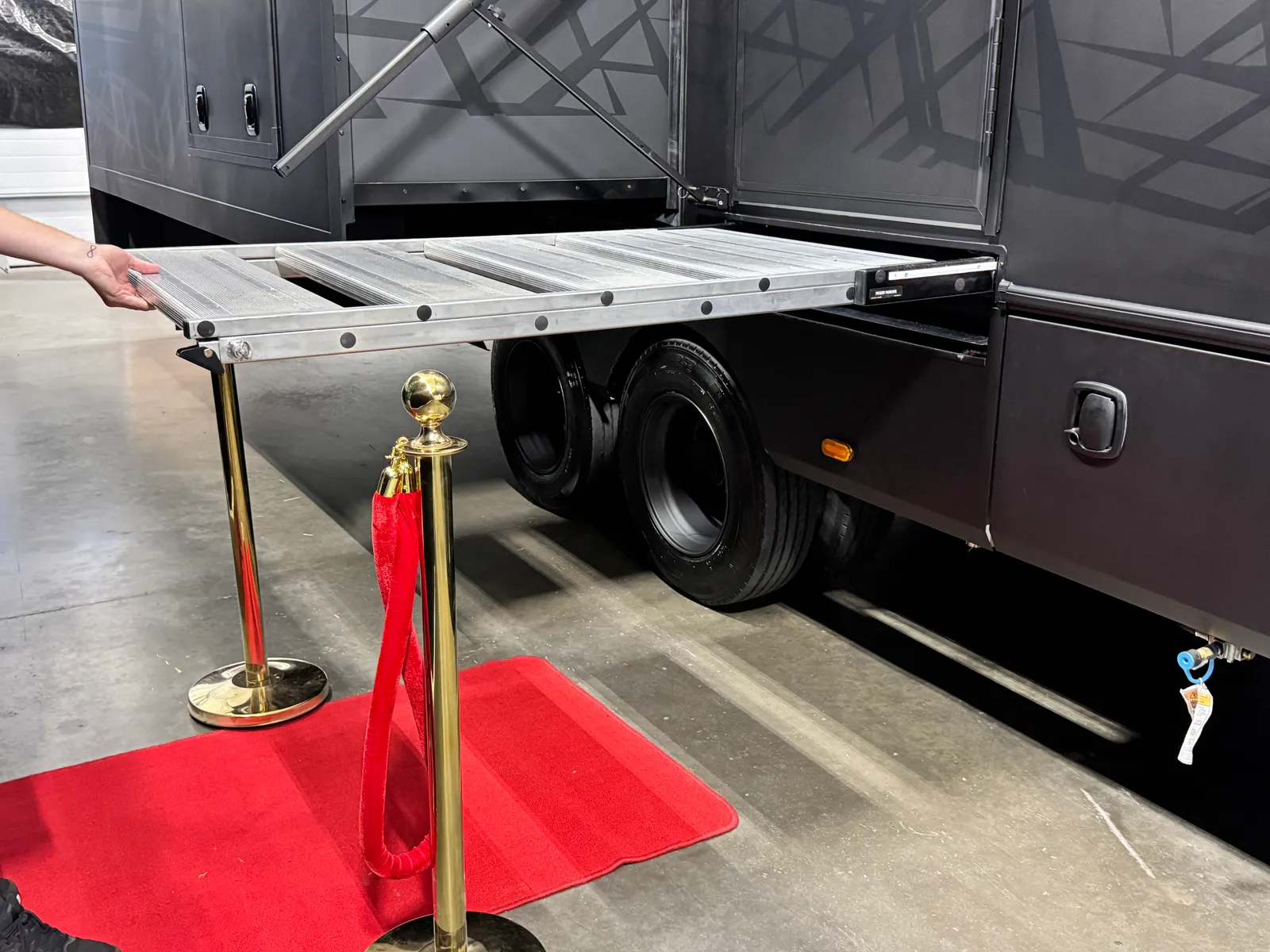 A hand folding the entry steps up into a flat platform beneath the coach.