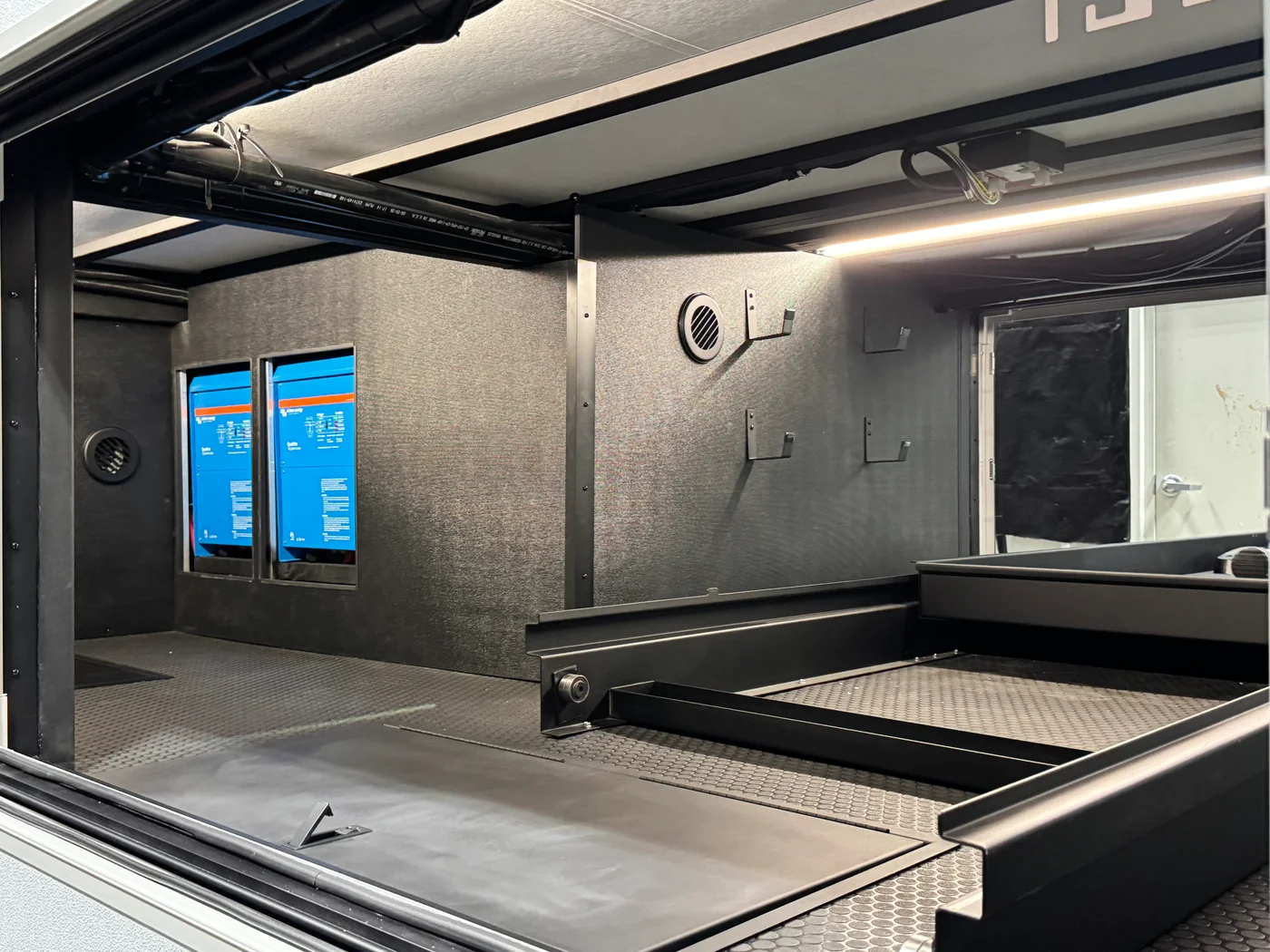 Open exterior pass-through compartment with lighting, equipment panels and a sliding tray.