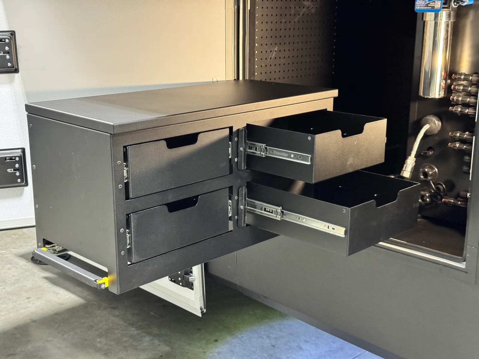 Exterior toolbox pulled out from its compartment, with two drawers open beside the utility bay.