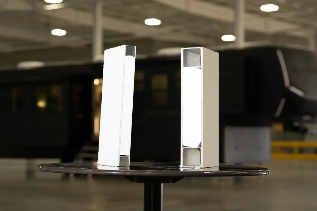 Two cut sections of the Aurum’s 3½-inch sidewall standing on a table, showing the aluminum framing and insulated core, with the Aurum behind.
